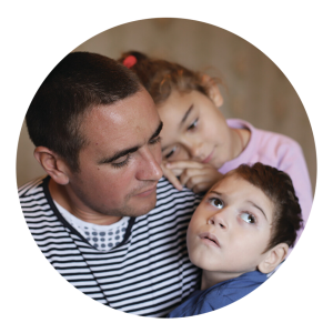A father cradling his disabled son and while his daughter leans on his shoulder