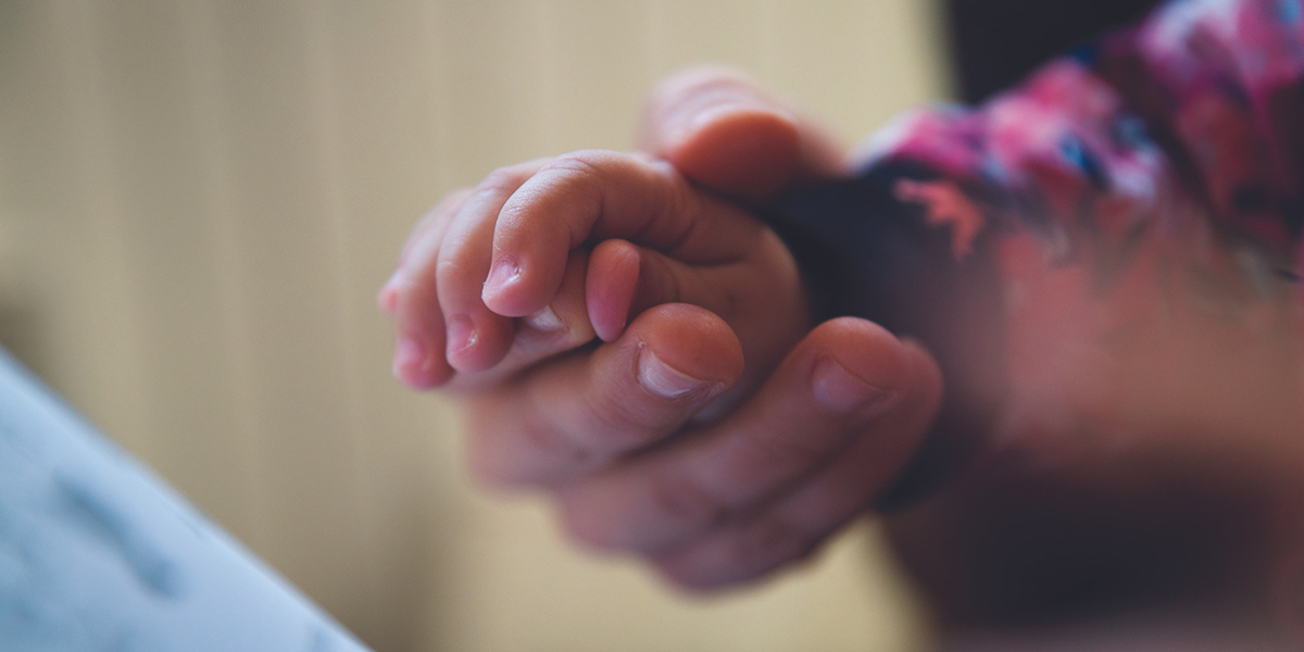 An adult holding a child's hand